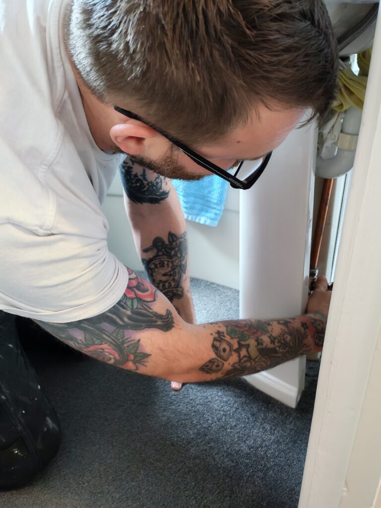 The Bedfordshire Plumber repairing pipework under a bathroom sink